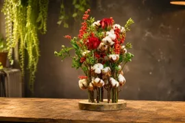 Dennis’ kerststuk op een houten schijf: met katoen, rozen en bessen