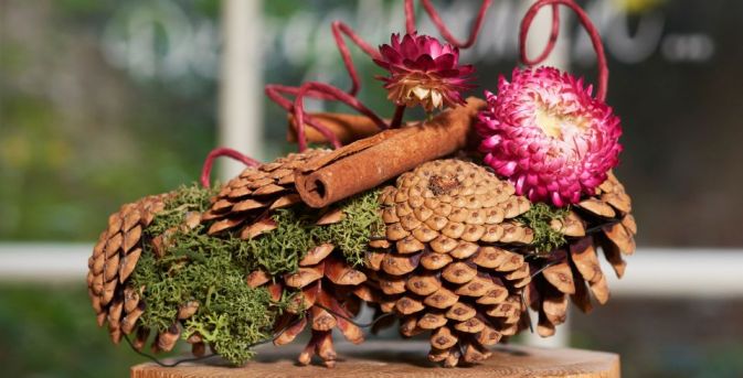 Herfstcreatie met dennenappels en strobloemen