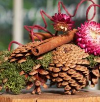 Herfstcreatie met dennenappels en strobloemen