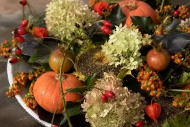 Herfst op een schaal: bloemstuk met pompoen, rozenbottels en bessen